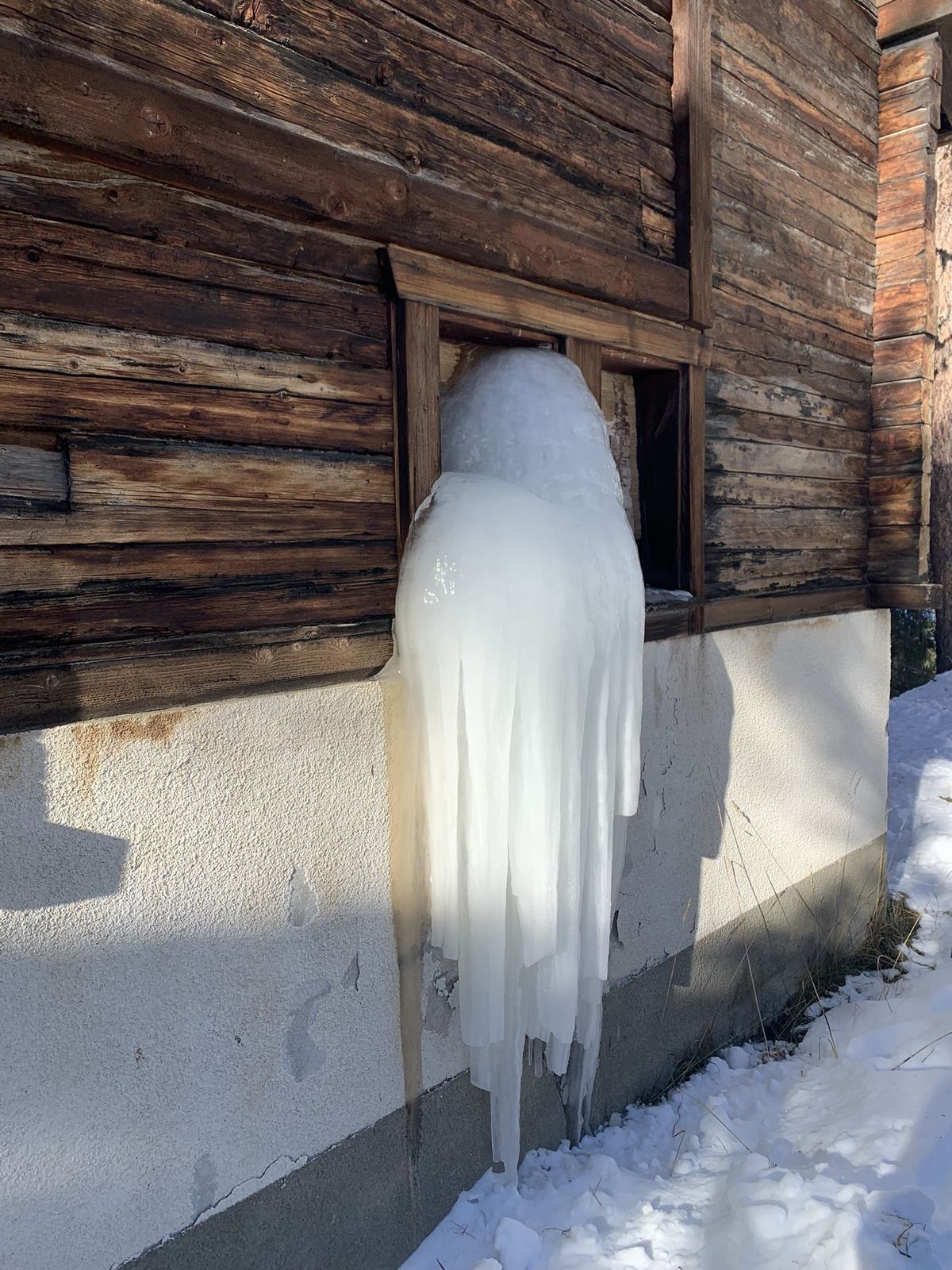 Stalactite géante sur façade de chalet, fuite figée par le gel